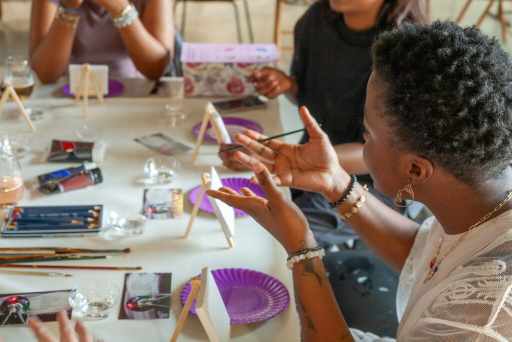 People painting at a table with art supplies.